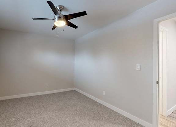 A room with a ceiling fan and carpeted floor.