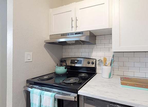 A kitchen with a stove and a white counter.