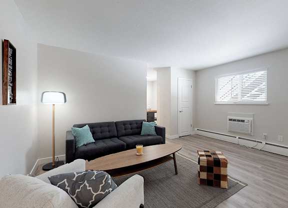 A living room with a black couch and a grey ottoman.