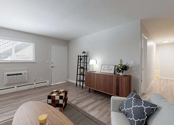 A living room with a couch, a coffee table, and a window with blinds.