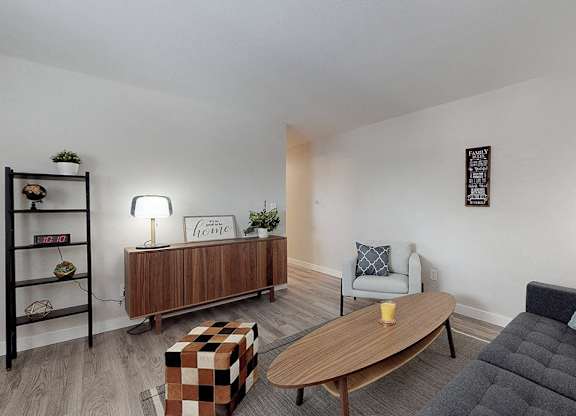 A living room with a black couch, a wooden coffee table, and a wooden bookshelf.