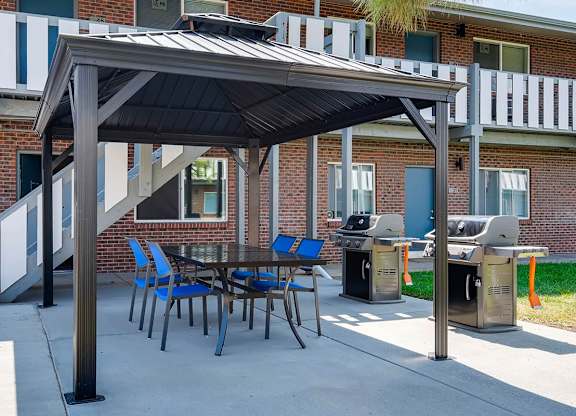 A patio with a table and chairs under a roof.