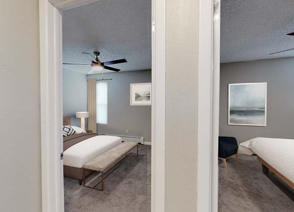 A bedroom with a bed, chair, and a ceiling fan.