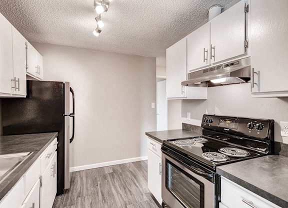 A kitchen with black appliances and white cabinets.