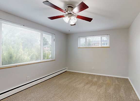A room with a ceiling fan and a window with blinds.