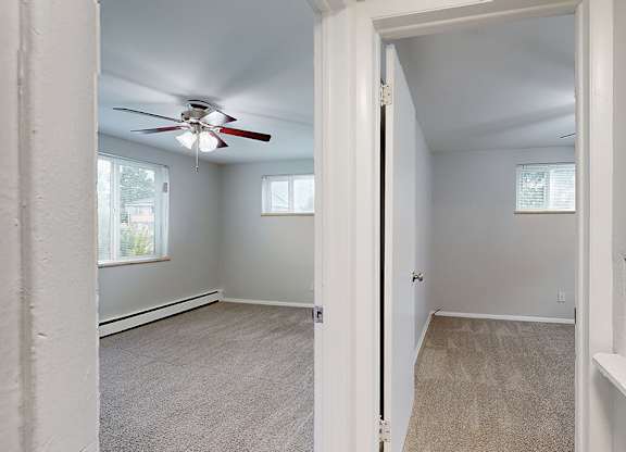 A room with a ceiling fan and carpeted floor.