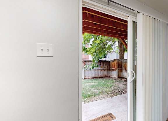 A white door with a window and a light switch on the wall.