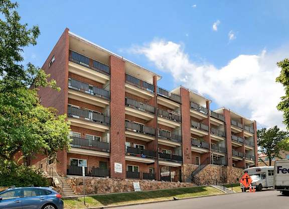 A large red brick building with a blue car parked in front.