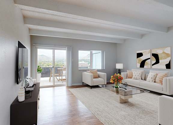 A modern living room with a white couch, a wooden floor, and a large painting on the wall.