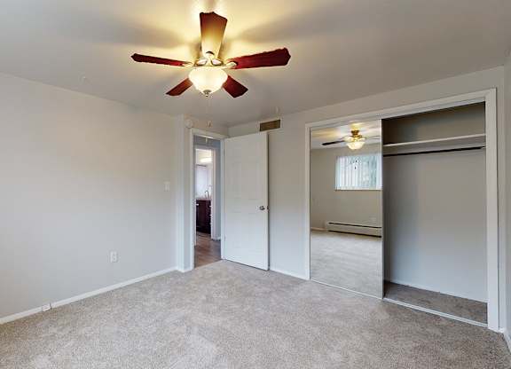 A room with a ceiling fan and carpeted floor.
