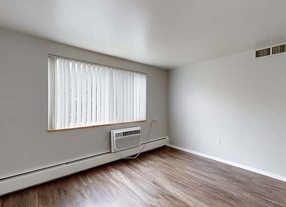 A room with a window and wooden flooring.