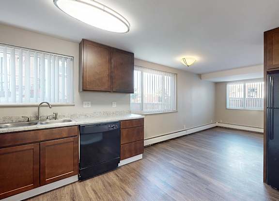 A kitchen with a black fridge and wooden cabinets.