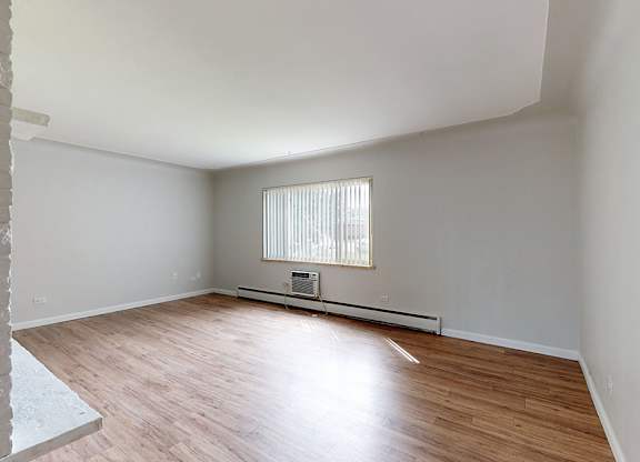 A room with wooden flooring and a window with blinds.