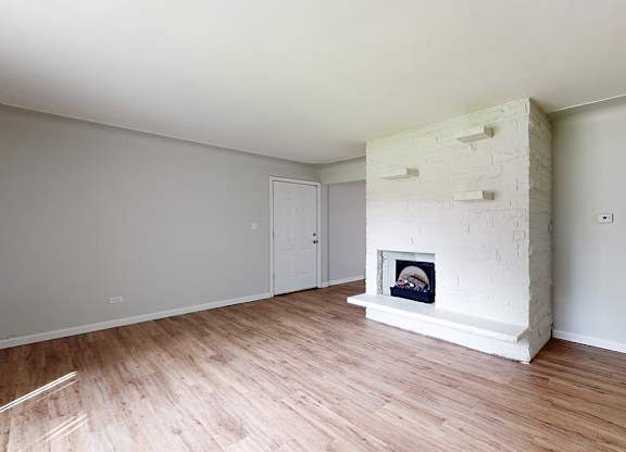 A white room with a fireplace and wooden floors.