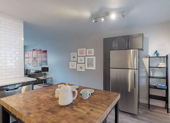 A kitchen with a wooden table and a stainless steel refrigerator.