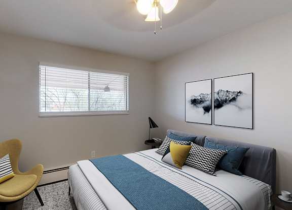 A bedroom with a bed, chair, and pictures on the wall.