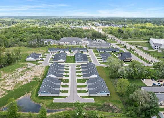 A bird's eye view of a residential area with houses and a pond.