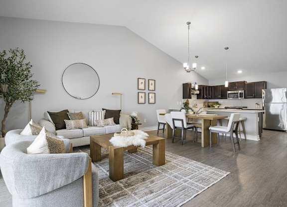 A modern living room with a grey sofa, a coffee table, and a dining table with chairs.