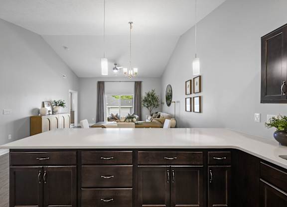 A kitchen with a white countertop and dark brown cabinets.
