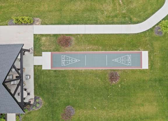 A tennis court is surrounded by a grassy area.