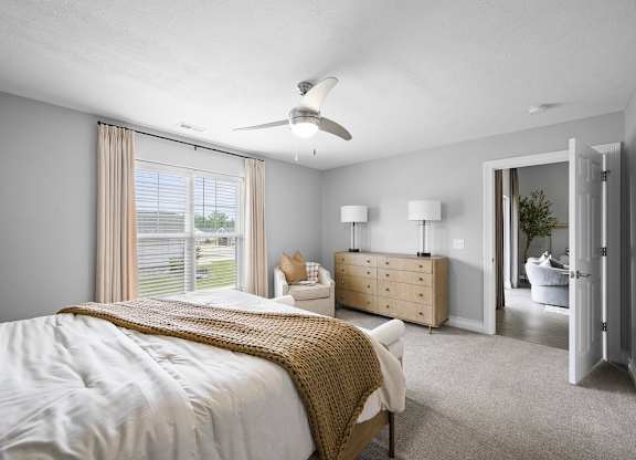A bedroom with a large bed and a ceiling fan.
