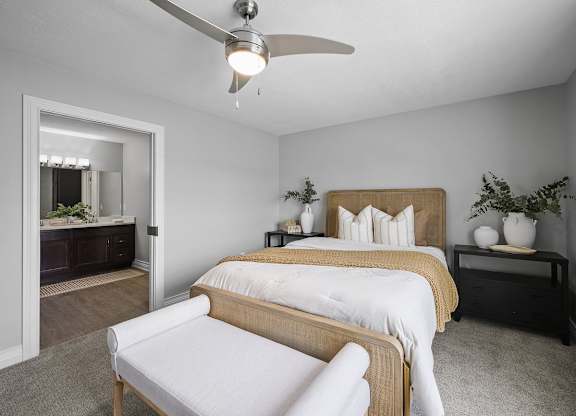 A bedroom with a bed, chair, and a ceiling fan.