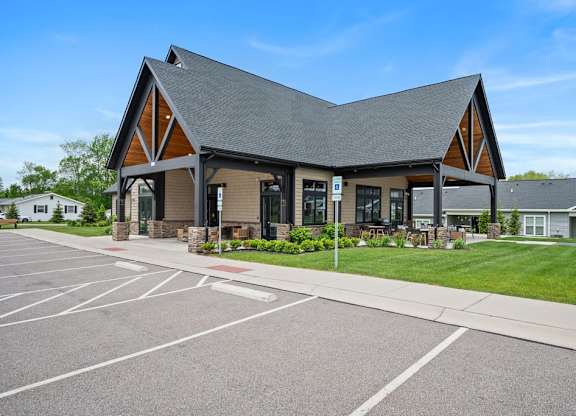 A building with a triangular roof and a parking lot in front.