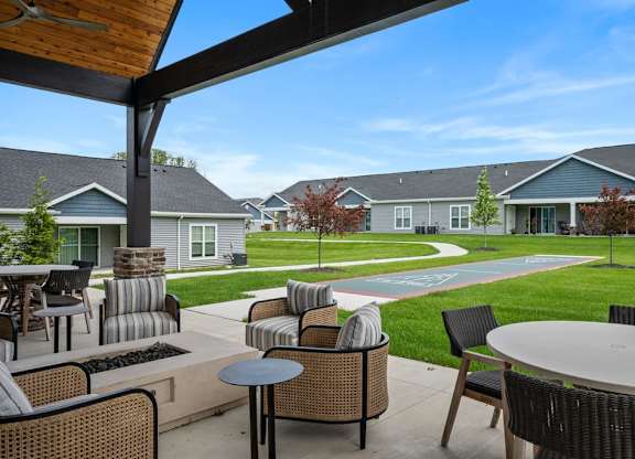A patio with a table and chairs overlooking a grassy area with houses in the background.