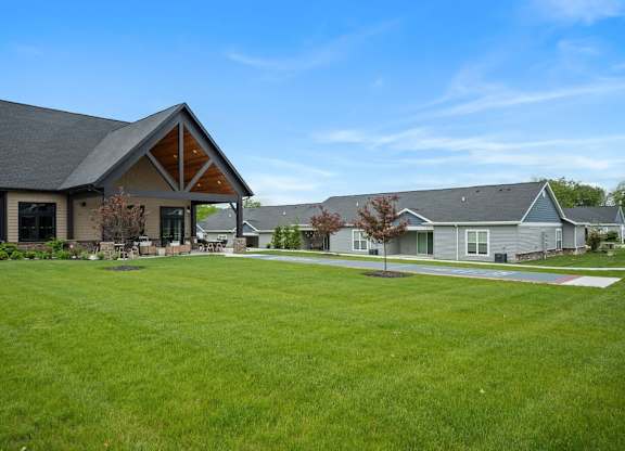 A large grassy area in front of a building with a grey roof.