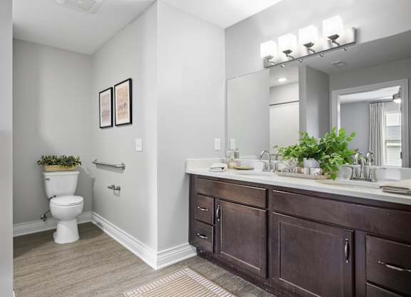 A bathroom with a toilet, sink, and mirror.