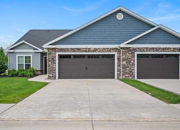 A house with a grey garage door and a stone pillar.