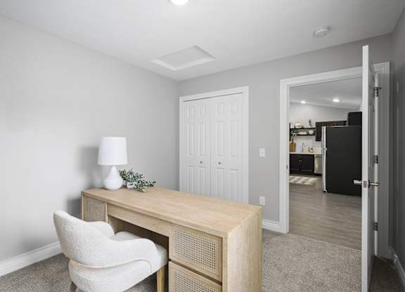 A white chair is in front of a wooden desk with a lamp and plant on it.