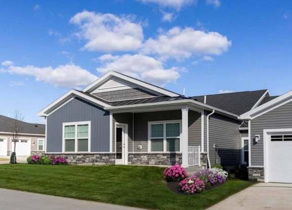 A grey house with a white garage door and windows.
