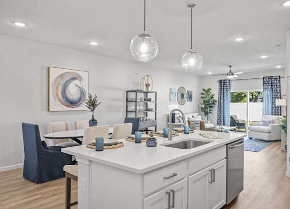 A modern kitchen with a dining area and a living room in the background.