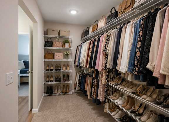 A walk in closet with a variety of shoes and clothes.