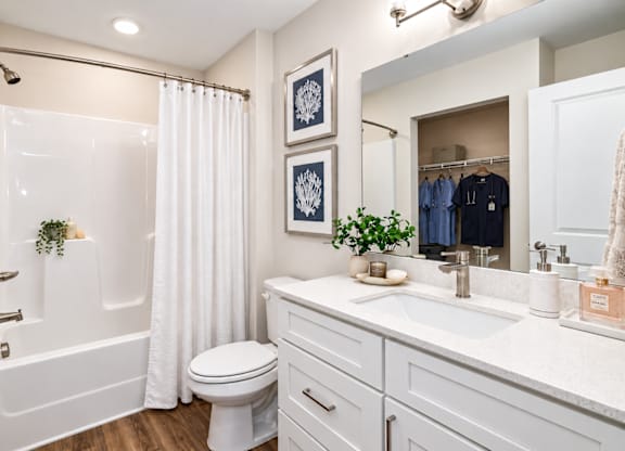 A white bathroom with a toilet, sink, and shower.