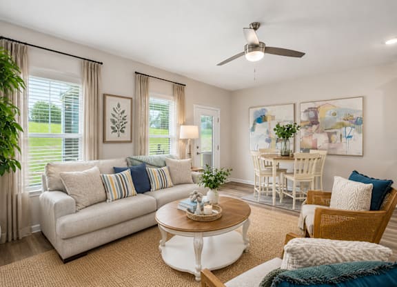 A living room with a white couch, a coffee table, and a ceiling fan.