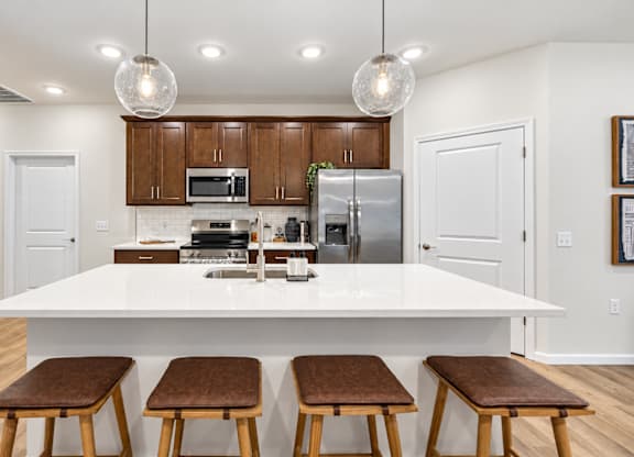 A kitchen with white countertops and brown stools.