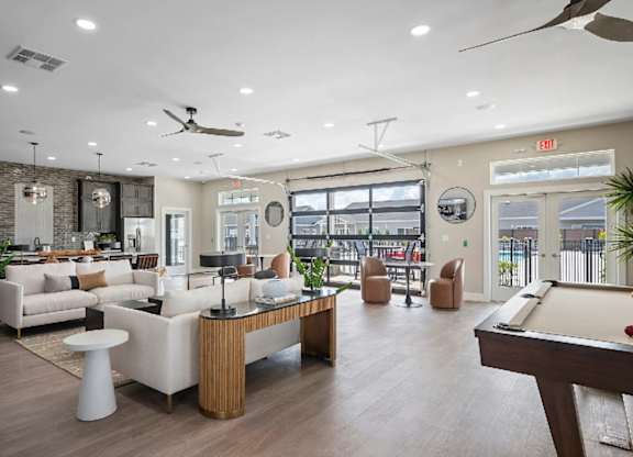 A well-lit room with a pool table and a bar area.