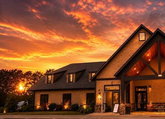 A house with a triangular roof and a stone facade is illuminated by the setting sun.