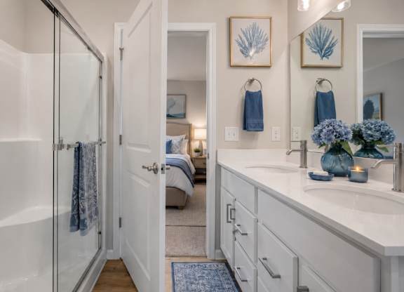 A bathroom with a white tub and sink, a mirror, and a blue rug.