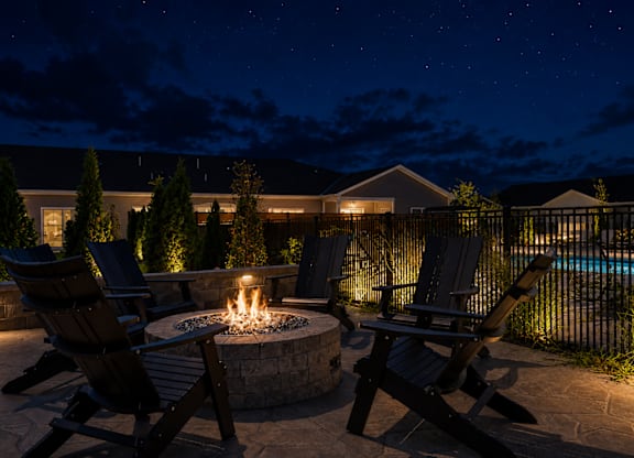 A backyard with a fire pit and chairs.