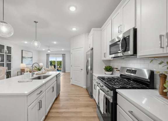 A modern kitchen with white cabinets and stainless steel appliances.