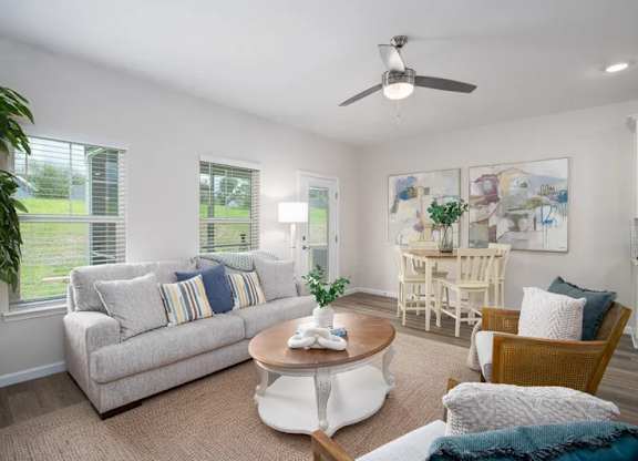 A living room with a couch, chairs, and a ceiling fan.