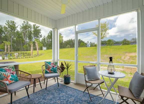 A sunny day in a white-framed porch with a table and chairs.