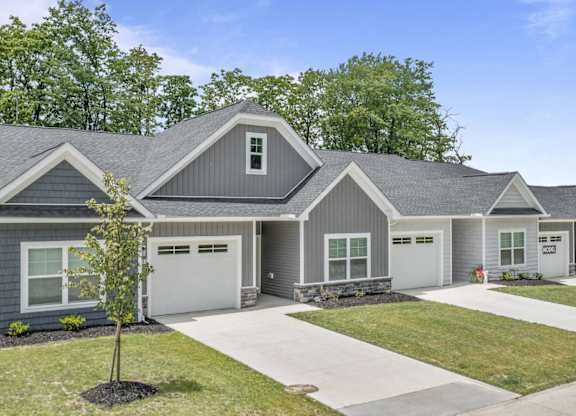 A row of houses with grey roofs and white garage doors.