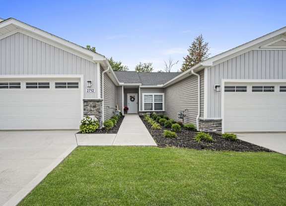 A two-story house with a garage on the left and a garage on the right.