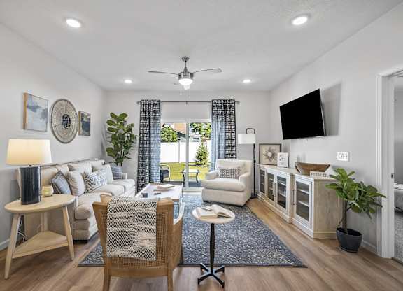A well-lit living room with a white sofa, a wooden chair, and a ceiling fan.