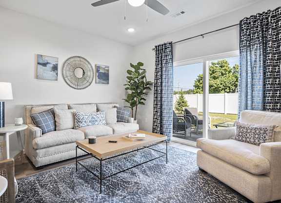 A living room with a beige couch, a coffee table, and a ceiling fan.