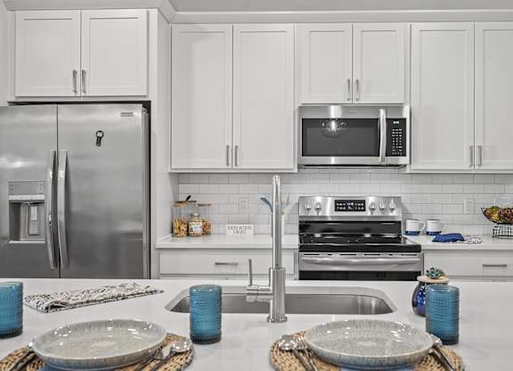 A modern kitchen with a stainless steel refrigerator, microwave, and oven.